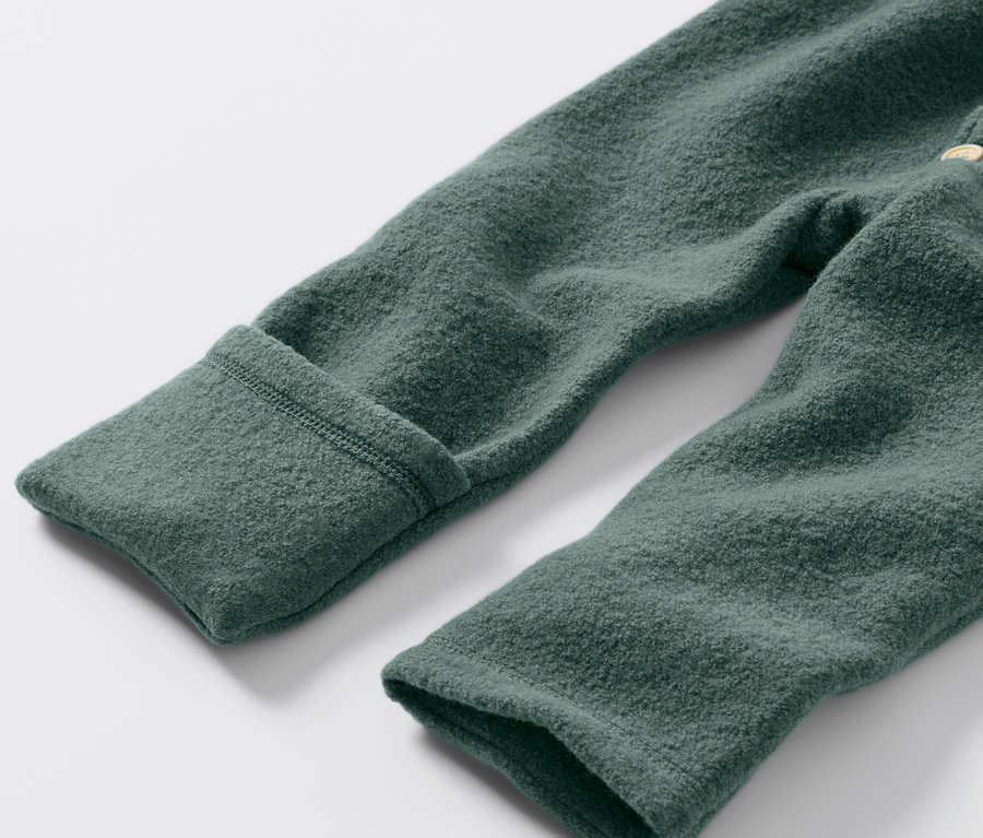 Detailaufnahme eines grünen Baby-Walkoveralls mit Merinowolle.