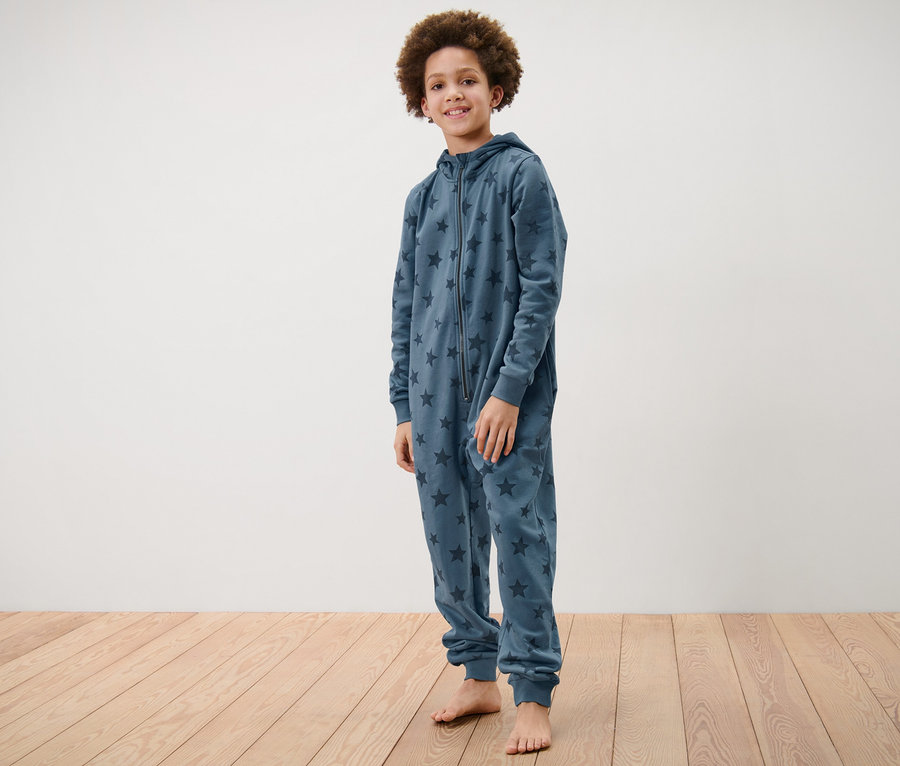 Ein Junge steht und trägt einen Kinder-Lounge-Overall mit Sternen.