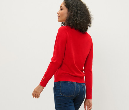Frau geht, trägt roten Feinstrickpullover, Jeans und Turnschuhe.