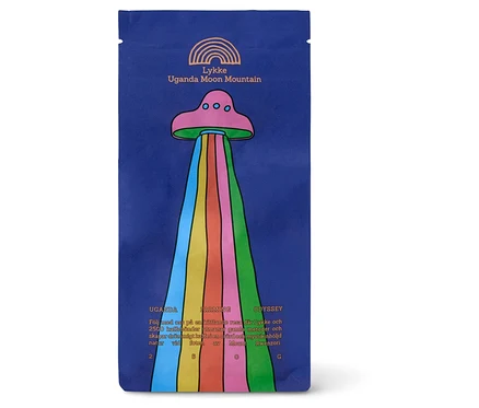 Blaue Kaffeepackung mit einem rosa UFO, das einen Regenbogenstrahl aussendet, und dem Text "Lykke Uganda Moon Mountain".