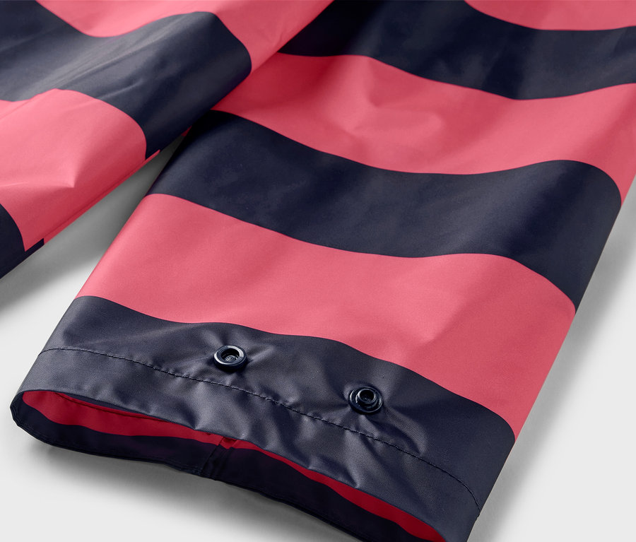 Detailansicht eines rosa-marineblau gestreiften Regenponchos mit Druckknöpfen.