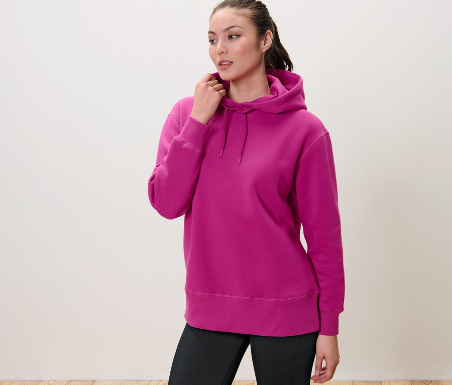 Frau berührt die Kapuze ihres Sweatpullovers mit Kapuze.