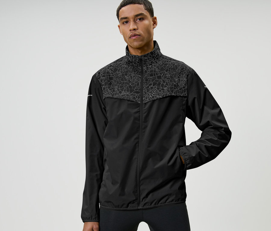 Mann posiert in Windprotection-Laufjacke, schwarz.