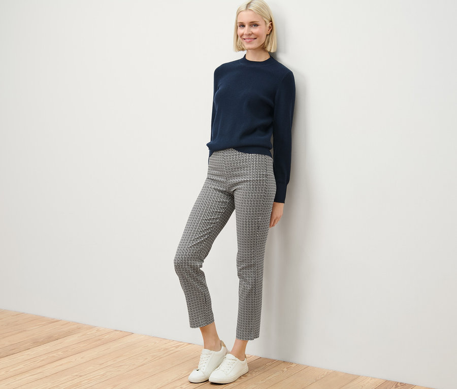 Frau posiert in marineblauem Pullover und bedruckter Stretchhose.