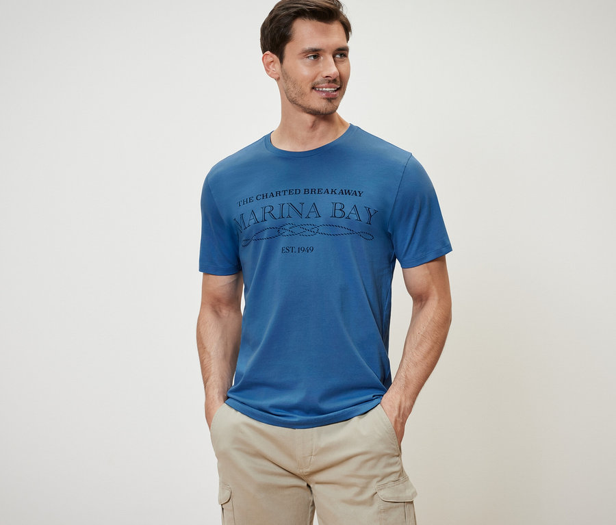 Mann trägt ein blaues T-Shirt und beige Cargoshorts.