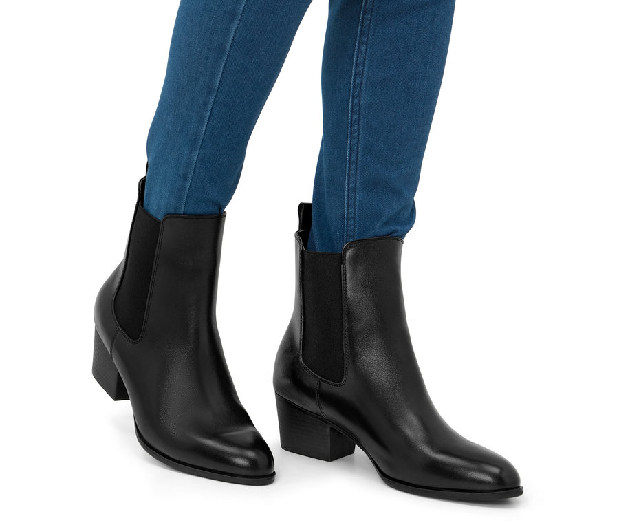 Beine in blauen Jeans, die Leder-Stiefeletten tragen.