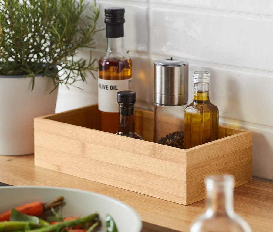 Kräuter im Topf und zwei Gewürzaufbewahrungsboxen neben einer Pfanne mit Gemüse.