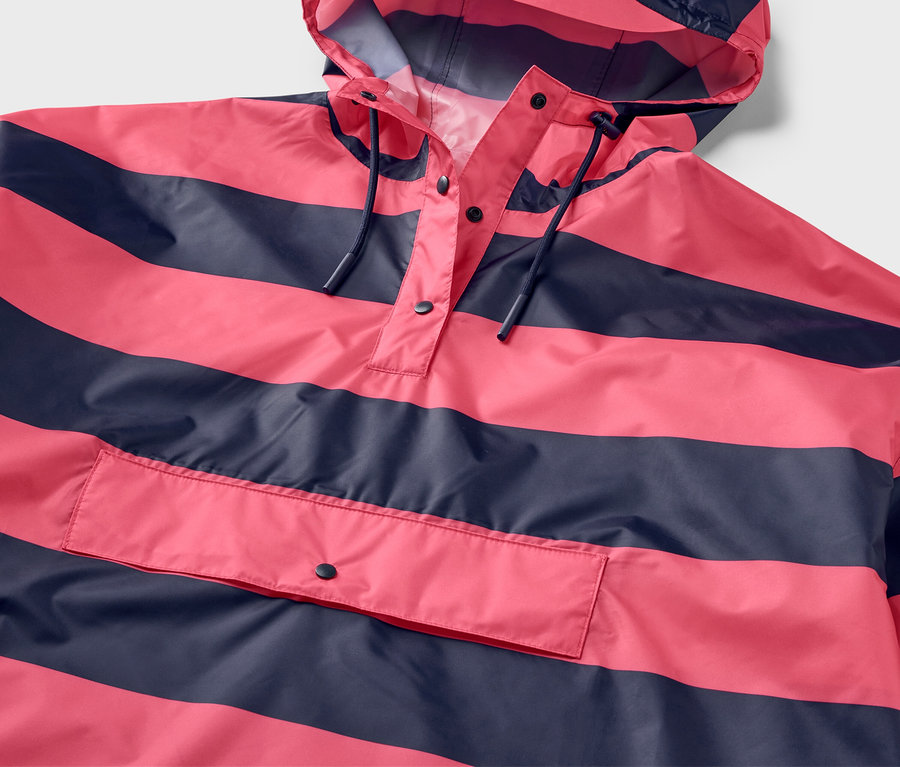 Detailansicht eines pink-dunkelblau gestreiften Regenponchos mit Kapuze und Tasche.