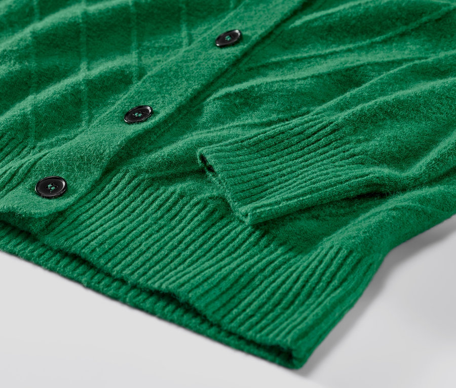 Detailansicht eines grünen Cardigans mit Strickstruktur.
