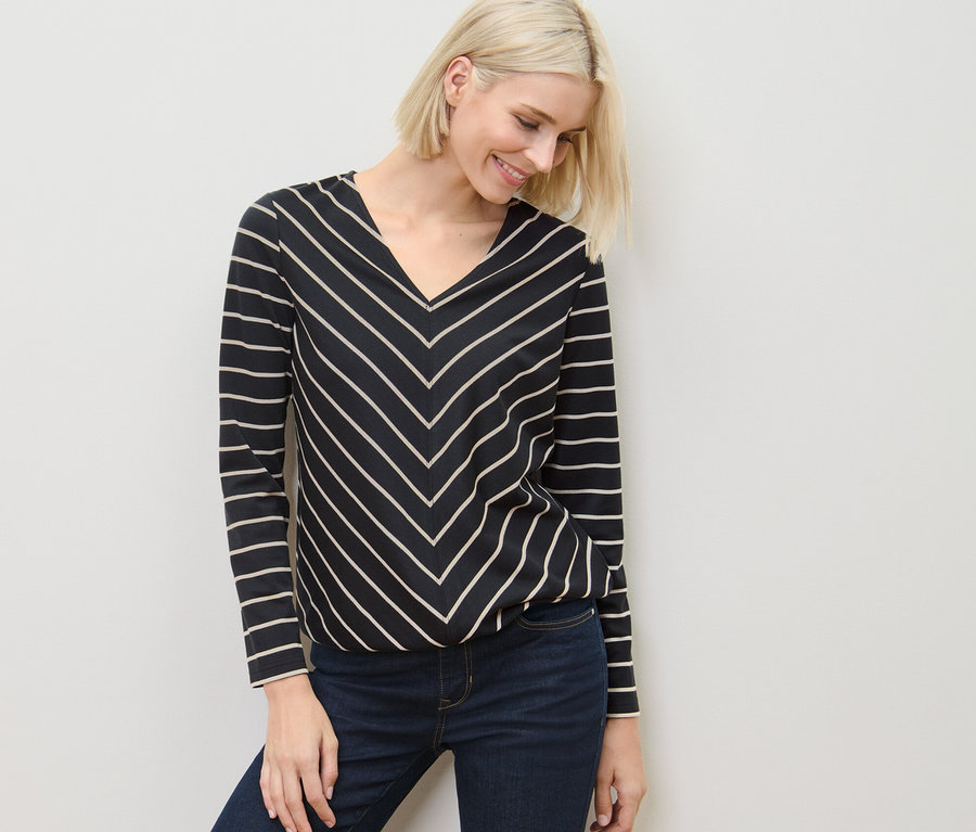 Frau trägt ein gestreiftes Blusenshirt aus Modal-Mix und Jeans.